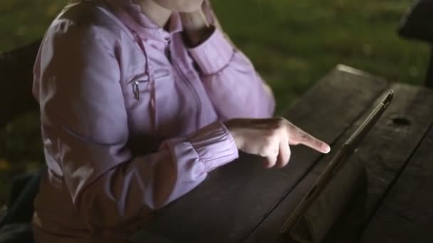 Fille avec la tablette électronique assis sur un banc dans le parc — Video