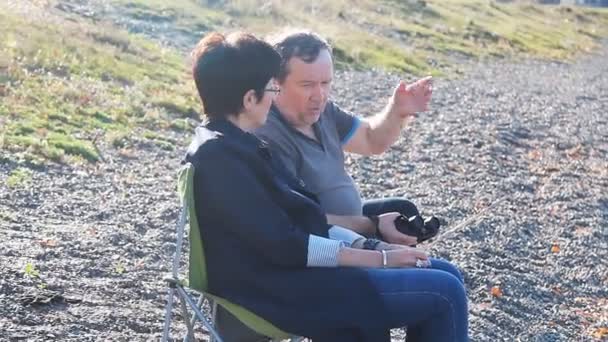 Зрелые влюбленные сидят на пляже и наслаждаются видом — стоковое видео