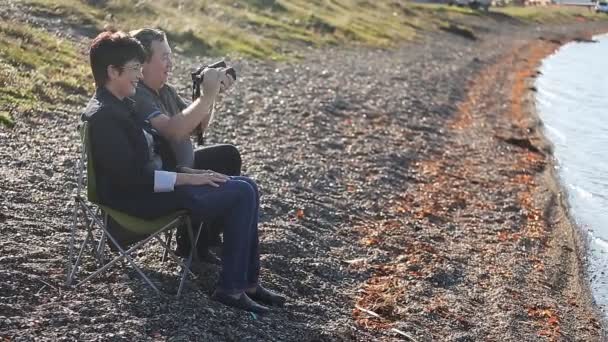 Mogna älskare sitter på stranden och njuter av utsikten — Stockvideo