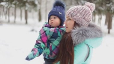 karlı kış ormandaki yürüyüşte kız bebek tutan mutlu anne