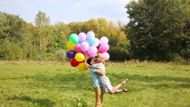 Aşık çift öpüşme ve çok renkli tutan slowmotion balonlar