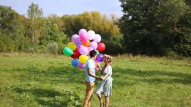 Aşık çift öpüşme ve çok renkli tutan slowmotion balonlar