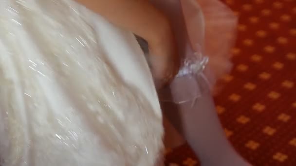 Bride putting a wedding garter on her leg — Stock Video