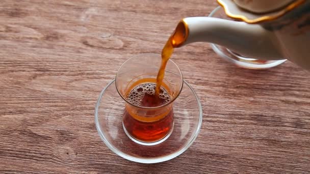 Despejando chá em uma xícara em uma mesa de madeira — Vídeo de Stock