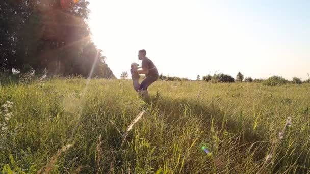Young boy walking with his father in a grassy field ins slowmotion — Stock Video
