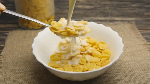 Frische Milch, die in Zeitlupe in eine Schüssel voller Cornflakes gegossen wird — Stockvideo