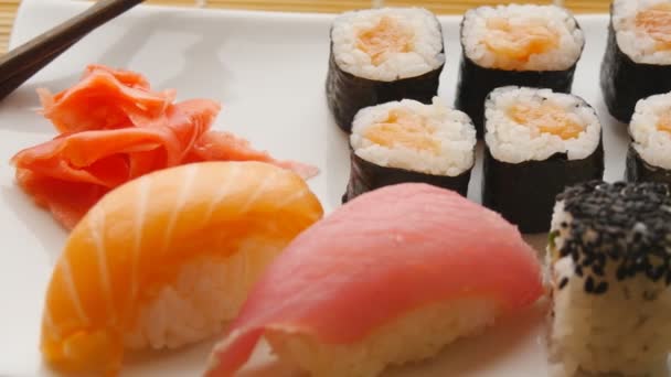 Various sushi on white plate on wooden background — Stock Video