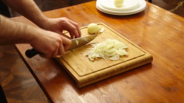 Las manos cortando cebollas en una tabla de cortar — Vídeo de stock