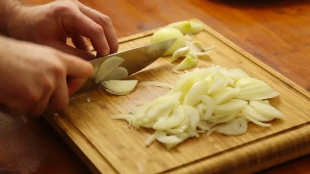 Las manos cortando cebollas en una tabla de cortar — Vídeos de Stock