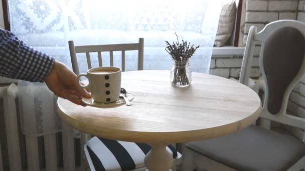 Un hombre pone una taza de café sobre la mesa en cámara lenta — Vídeos de Stock