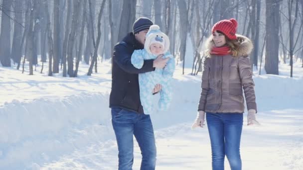 Pai e mãe caminham no parque com a criança na lentidão do inverno — Vídeo de Stock