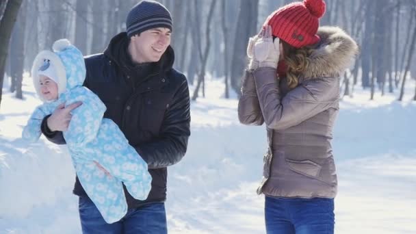 Vater und Mutter spazieren mit Kind im Park bei winterlicher Zeitlupe — Stockvideo