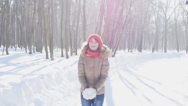 Счастливая молодая женщина бросает снег в парке, медленное движение — стоковое видео
