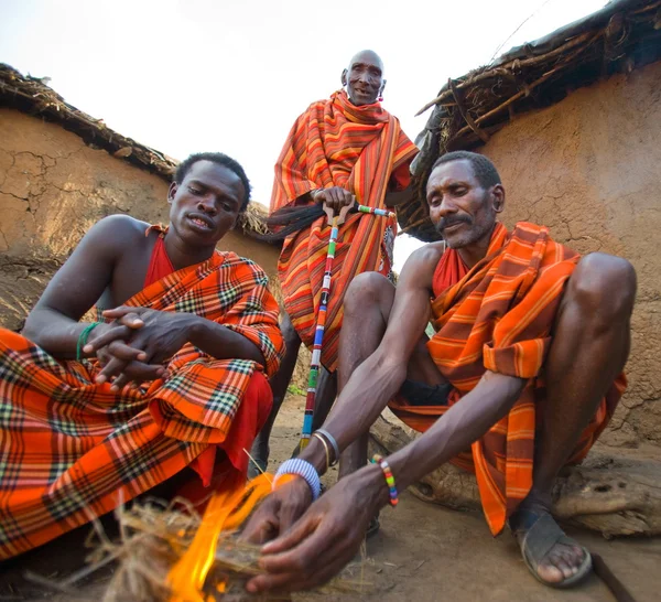 Men gathered trying to light a fire — Stock Photo, Image