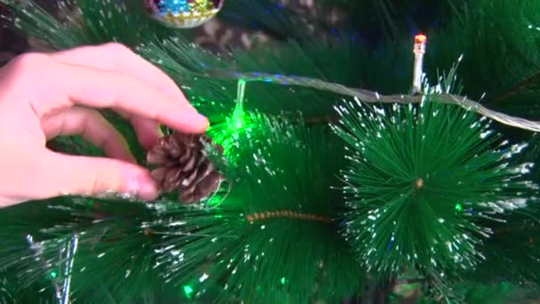 Handen close-up hangen een speeltje in de vorm van een kegel aan de kerstboom — Stockvideo