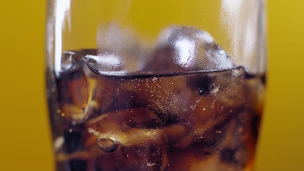 用冷饮摇匀了一杯清澈的玻璃杯 倒入冷饮 一杯可乐 在模糊的光线和模糊的背景下 有飞溅气泡的冰可乐运动缓慢 — 图库视频影像