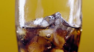 Soğuk sodayı dolduruyorum. Bir bardak kola. Bulanık ışık ve bulanık arkaplan üzerinde su sıçratan baloncuklu buzlu kola yavaş çekim.