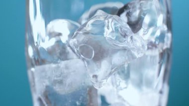 Soda ya da kırmızı sıvıyla doldurulmuş bir bardaktaki buz küplerini yakın plan çek. Kromakey için mavi ekran arka planında kokteyl