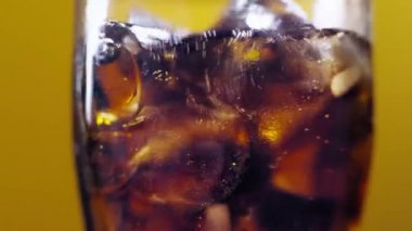 Soğuk bir kokteyl ile temiz bir bardağı sallamak. Soğuk soda dolduruyorum. Bir bardak kola. Bulanık ışık ve bulanık arkaplan üzerinde su sıçratan baloncuklu buzlu kola yavaş çekim.