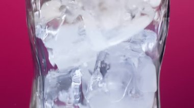 Soda için şeffaf bir bardakta buz küpleri ya da anahtarlama için parlak bir arka planda Kokteyl