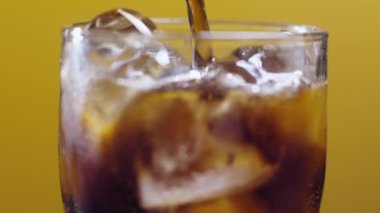 Bir bardak meşrubat. Su sıçratan köpüklü buzlu içecek bulanık bir ışıkta yavaş çekim, bulanık arkaplan.