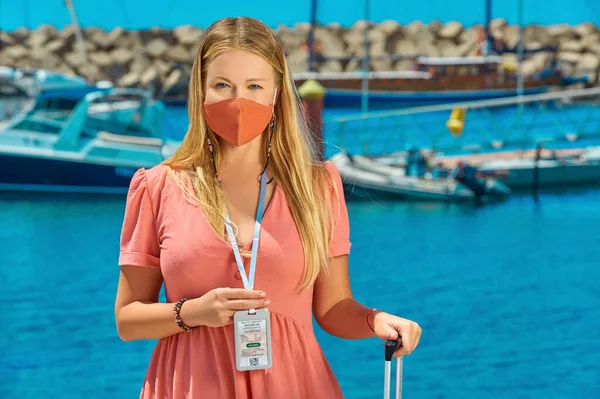 Rıhtımdaki turist aşı pasaportunu gösteriyor. Seyahat belgeleriyle bir yolculuğa çıkmış insan. İnsanda Covid-19 aşı kartı var. Yüz maskesi takan kadın tıbbi konsepti belgeyi gösteriyor