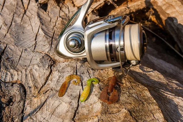 Fishing reel and various kind of baits on the natural background — Stock Photo, Image