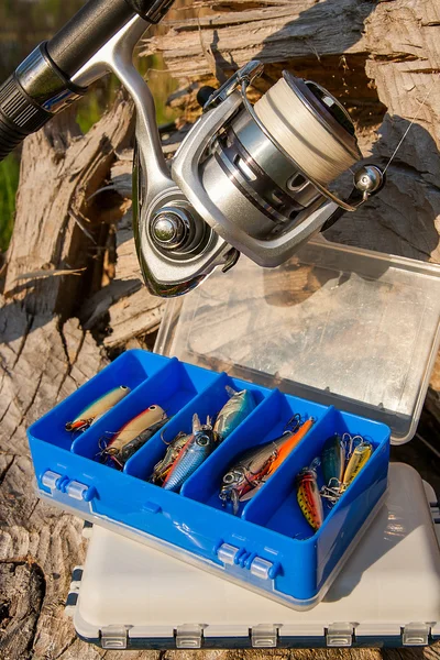 Fishing rod with reel and various kind of baits on the natural b — Stock Photo, Image
