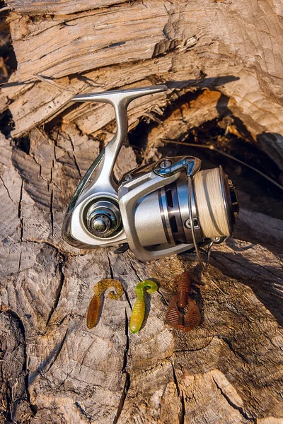 Carrete de pesca y varios tipos de cebos en el fondo natural — Foto de Stock