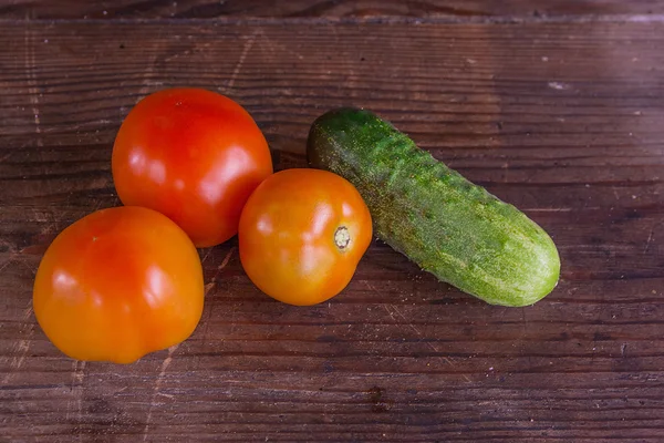 Vue rapprochée des tomates fraîches et mûres et des concombres sur le dos en bois — Photo