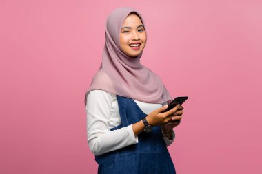 Genç Asyalı kadın cep telefonu kullanarak gülümsüyor.