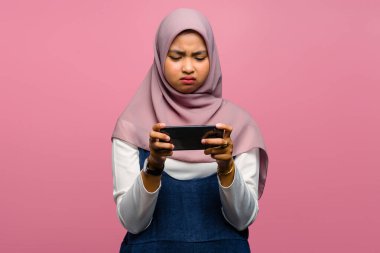 Genç Asyalı kadın video oyunu oynuyor ve mutsuz görünüyor.