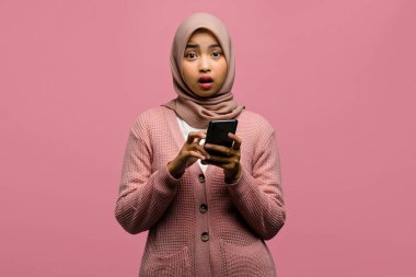 Güzel Asyalı bir kadının portresi şaşırmış ve elinde akıllı telefon tutuyordu.