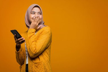 Güzel Asyalı bir kadının elinde boş bir telefonla neşeli bir şekilde beklemesi.