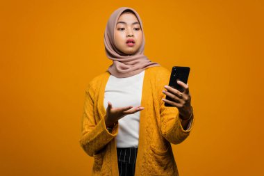 Güzel Asyalı kadın şok olmuş bir suratla akıllı telefon kullanıyor.