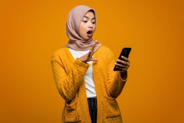 Şok olmuş bir ifadeyle cep telefonu kullanan güzel bir Asyalı kadının portresi.