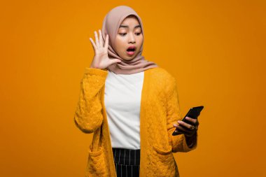 Şok olmuş bir ifadeyle cep telefonu kullanan güzel bir Asyalı kadının portresi.