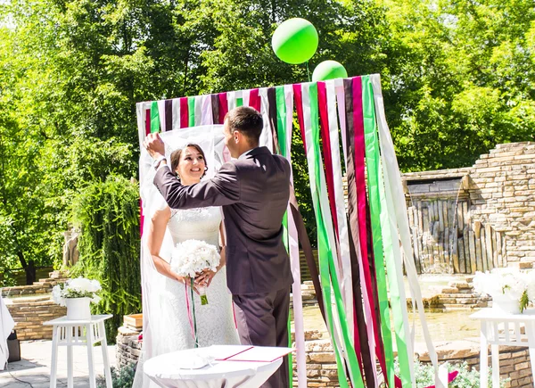 Frisch verheiratetes Paar unter Hochzeitsbogen — Stockfoto
