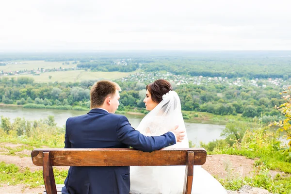 Ρομαντικό γάμο ζευγάρι που κάθεται σε ένα παγκάκι στο πάρκο — Φωτογραφία Αρχείου