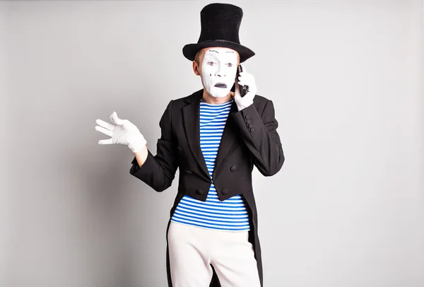 Крупним планом молодий актор розмовляє по мобільному телефону на сірому фоні — стокове фото