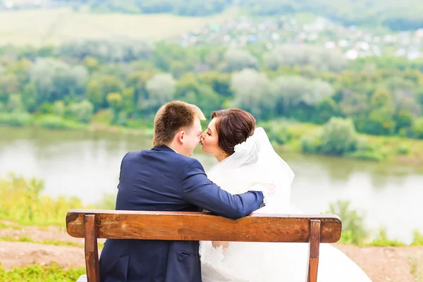 Романтическая свадебная пара, сидящая на скамейке в парке — стоковое фото