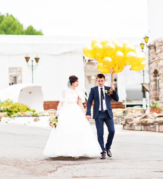 風船で野外を歩いている若い結婚式のカップル — ストック写真