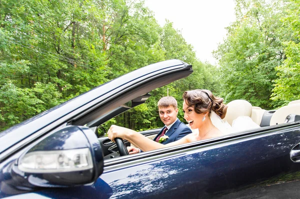 Casal jovem bonita noiva e noivo posando em cabriolet — Fotografia de Stock