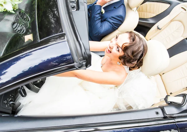 Casal jovem bonita noiva e noivo posando em cabriolet — Fotografia de Stock