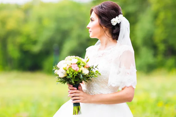 Gyönyörű menyasszony lány csokor virágot, szabadban álló esküvői ruha — Stock Fotó