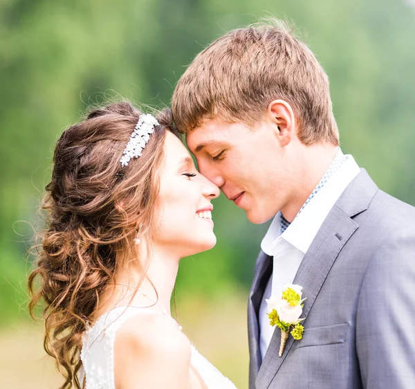 Schöne Braut und Bräutigam stehen im Gras und küssen sich. Hochzeitspaar — Stockfoto