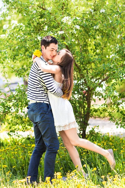 Loving couple under blossoming branches spring day. Young adult  brunette man and woman kissing in fresh blossom apple or cherry trees garden. sweet kiss