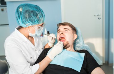 Kadın dişçi hastalarının dişlerinde çalışıyor.