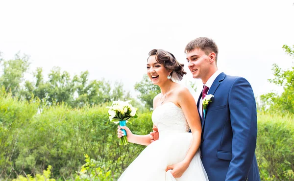 O noivo e a noiva num parque. Vestido de noiva. Buquê de casamento nupcial de flores — Fotografia de Stock