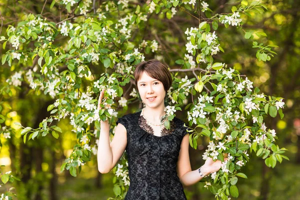 Portrait de jeune femme dans le jardin fleuri au printemps. Fleurs d'amande fleurit. — Photo